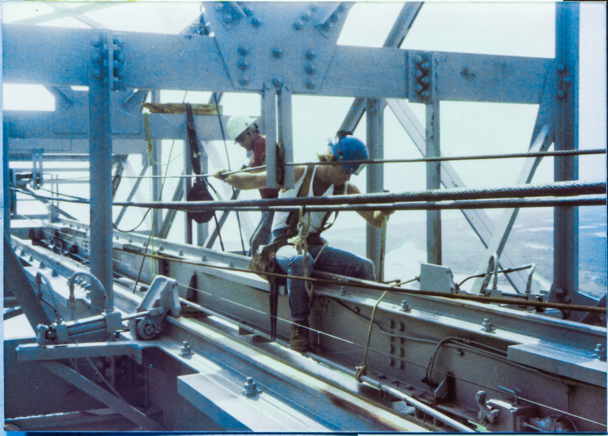 Image 061. Union Ironworker James Dixon, from Local 808, working for Ivey Steel at Space Shuttle Launch Complex 39-B, Kennedy Space Center, Florida, sits on one of the rails which carries the Hammerhead Crane Hook Trolley, as work proceeds beneath him, out of view, installing the TPS Inspection Spider Basket Trolley Support Extensible Pipe Boom to the Hammerhead Crane. Photo by James MacLaren.